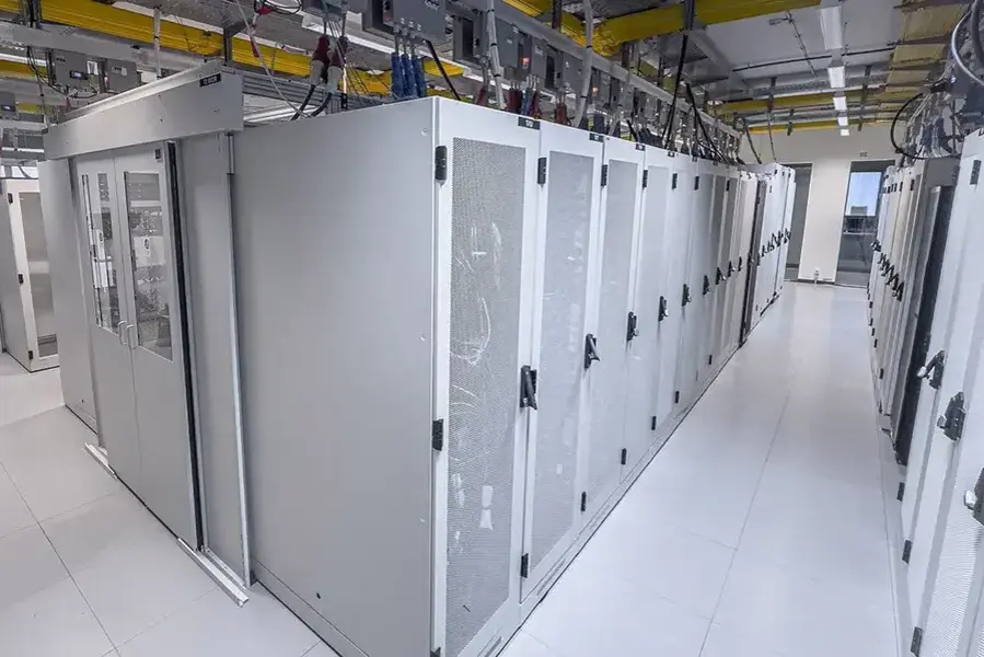 A view of a modern data center featuring rows of server racks with metallic casing and organized wiring overhead.