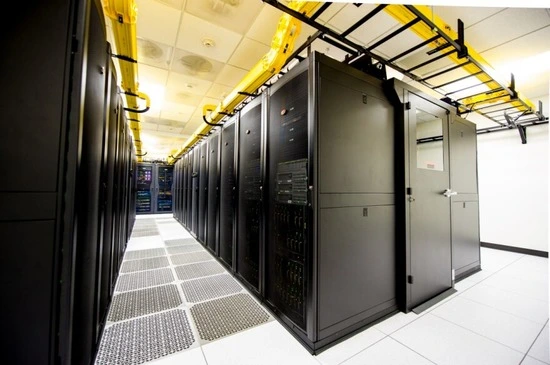 Interior view of a data center featuring rows of black server racks and overhead cable management systems.